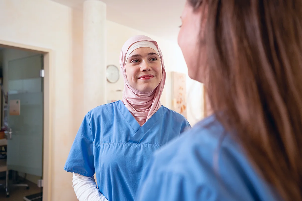 Mitarbeiterinnen am Empfang im Gespräch, aufgenommen über die Schulter.